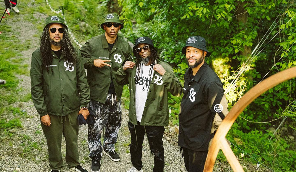 Four men standing outside with trees in the background