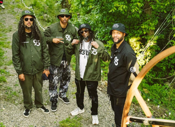 Four men standing outside with trees in the background