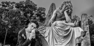 Man next to a graveyard sculpture, imitating its position