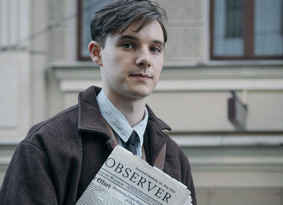 Young man holding a newspaper on the street