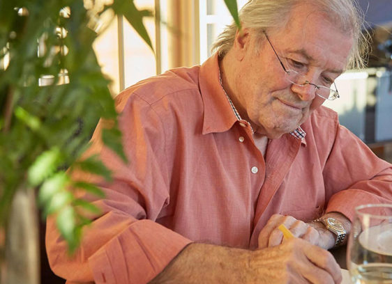 Man sitting in a kitchen or den looking at a book