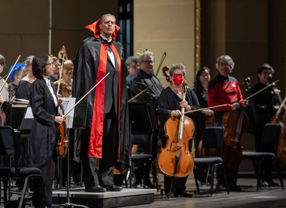 Orchestra conductor on stage wearing Dracula costume