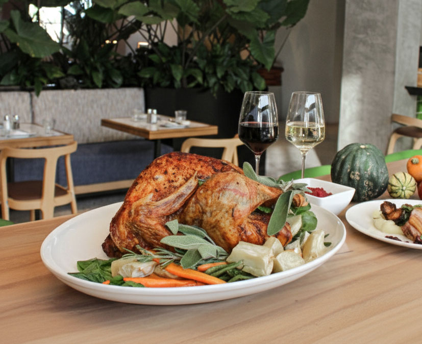 Turkey on a plate surrounded by vegetables and two glasses of wine