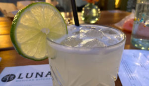 Cocktail with salted rim and lime garnish on a bar