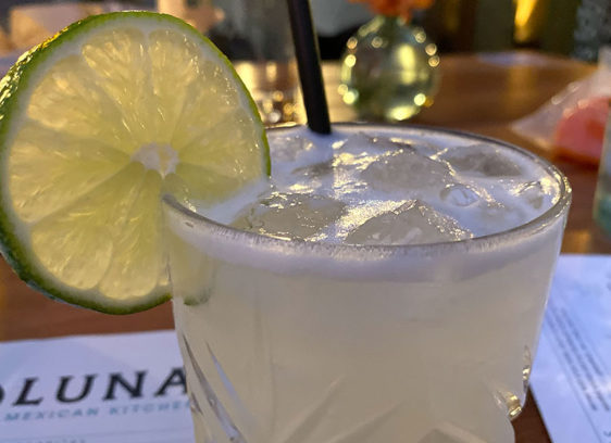 Cocktail with salted rim and lime garnish on a bar