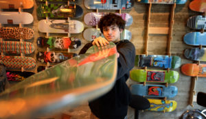 Young person pointing a skateboard directly at the camera