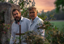 Two men walking in a graveyard at dusk