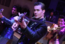 Three men rehearsing with guitars and looking into the camera