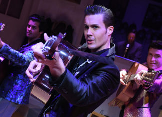 Three men rehearsing with guitars and looking into the camera