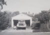 Archival black-and-white photo of an open garage with a car being worked on