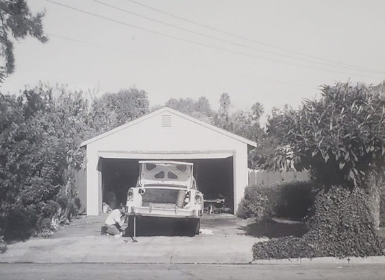 Archival black-and-white photo of an open garage with a car being worked on