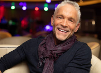 Smiling man sitting on a couch in a darkened auditorium