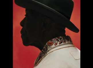 Man in silhouette wearing a black hat and a white shirt on a solid red background